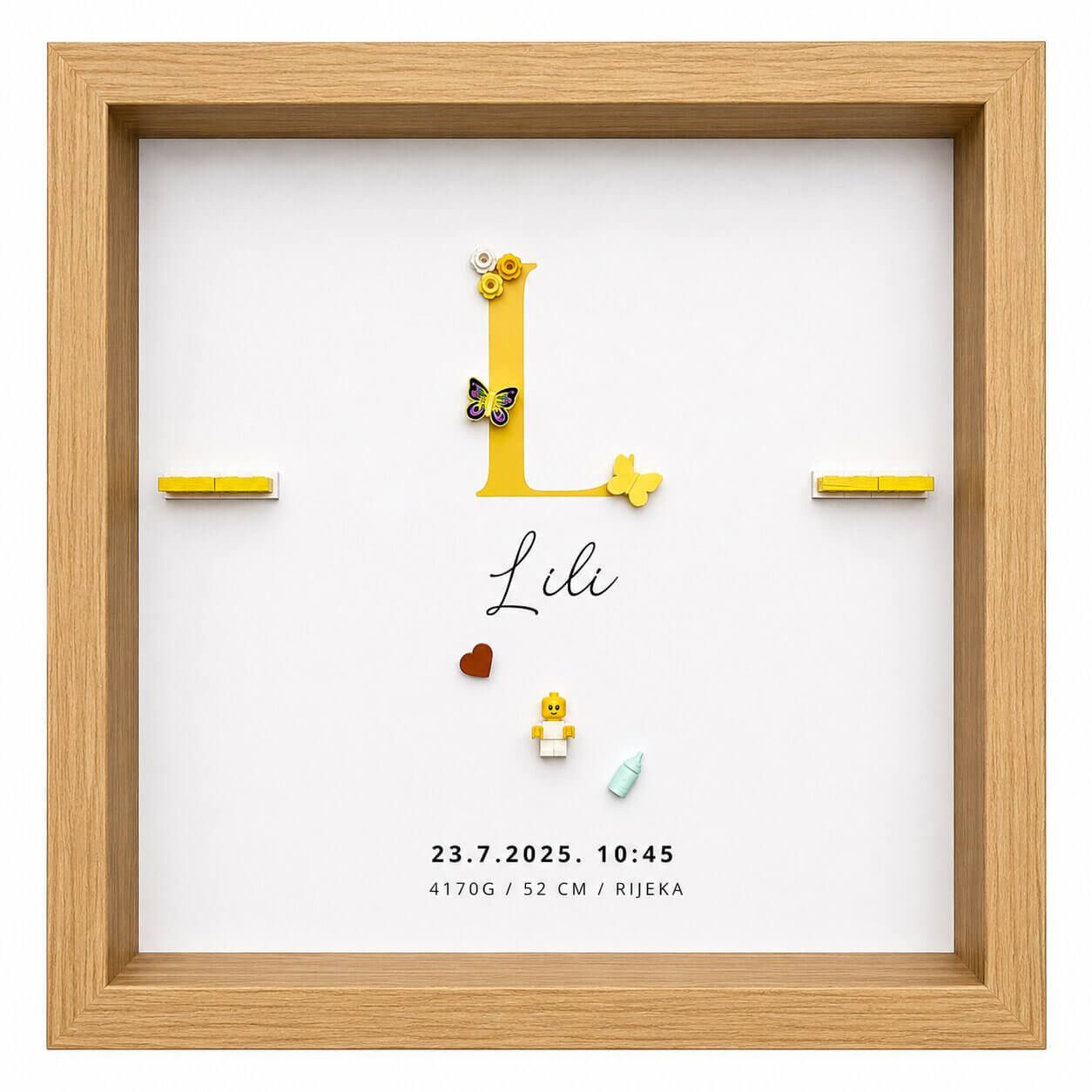 Personalizirani LEGO okvir za novorođenče Lili u drvenom okviru sa žutim slovom, figuricom bebe, leptirićima, srcem i podacima o rođenju.